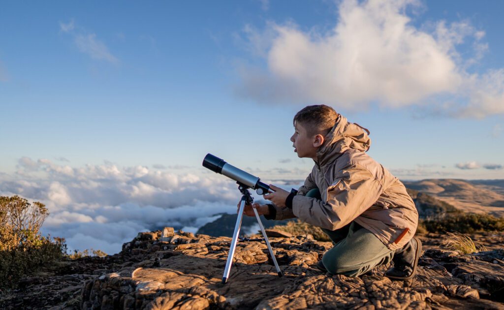 Young explorer high in the mountains with telescope stock photo