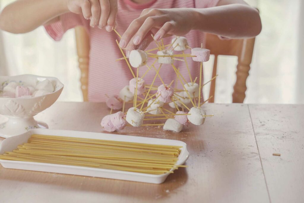 Stock photo of a child building a structure out of toothpicks and marshmallows.