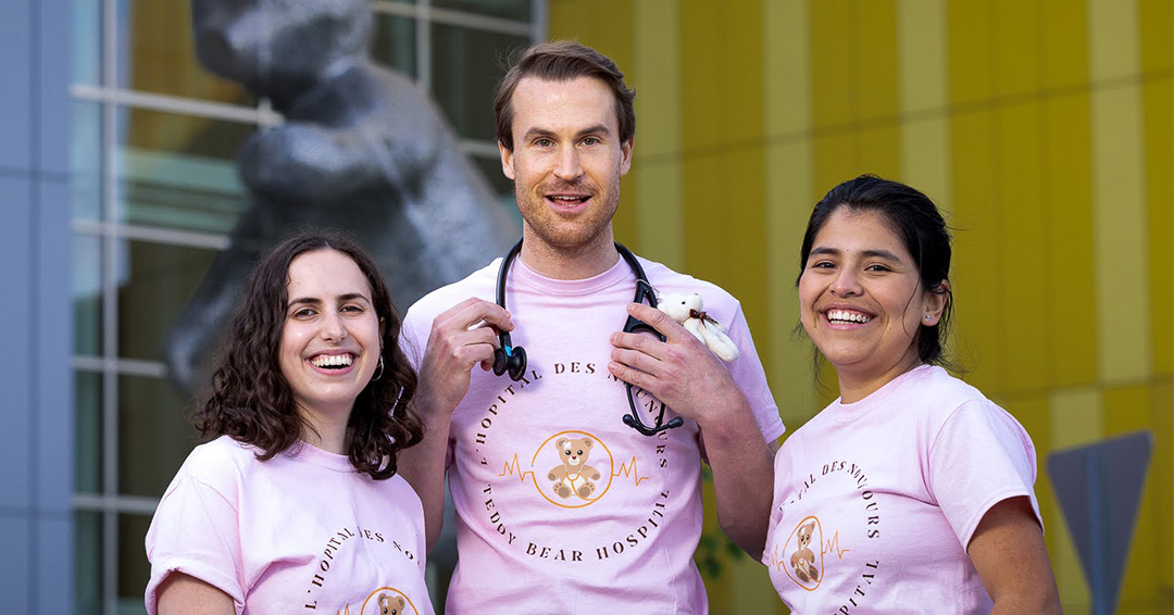 Three students in pink t-shirts standing outside the Montreal Children's hospital.