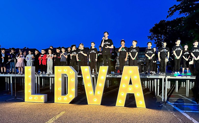 Large illuminated sign that says LDVA in front of a cheering crowd at night.